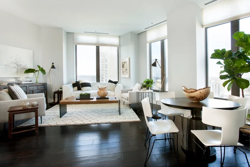Salón de una vivienda reformada: suelo de madera oscura, paredes claras y ventanales de suelo a techo.